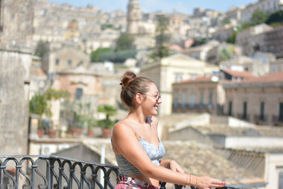 Young woman looking at cityscape against buildings in city