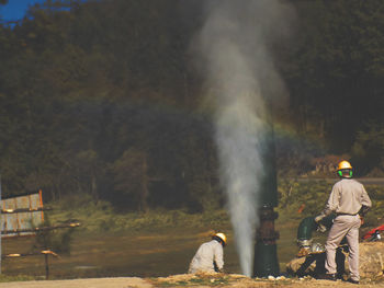 Rear view of man sitting by water