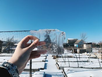 Person holding ice cream against blue sky