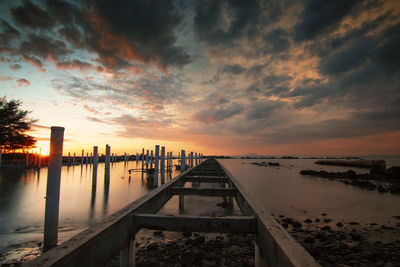 Pier over sea against sky during sunset