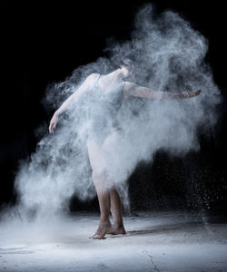 Full length of ballet dancer against black background