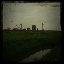 Grassy field against cloudy sky