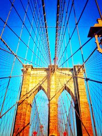 Low angle view of suspension bridge against blue sky