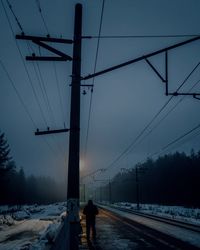 Rear view of snow covered railroad tracks against sky during winter