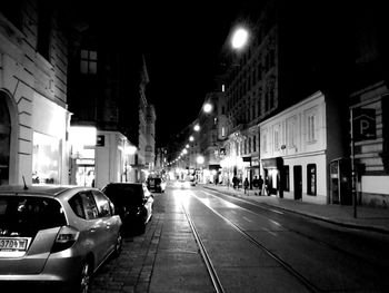 Cars on city street amidst buildings at night