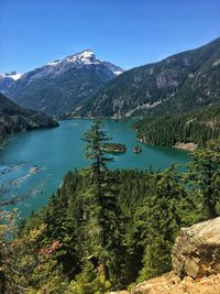 Scenic view of lake and mountains against clear blue sky