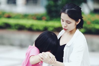 Close-up of mother and daughter holding hands while standing outdoors