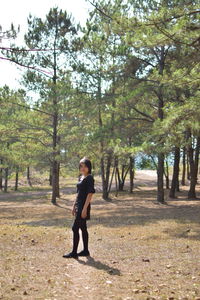 Full length portrait of woman standing in forest