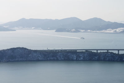 Scenic view of sea by mountains against sky