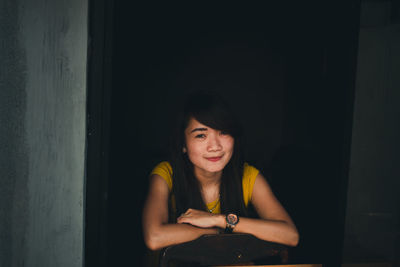 Portrait of young woman sitting on chair at home