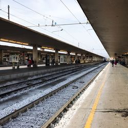 People at railroad station against sky