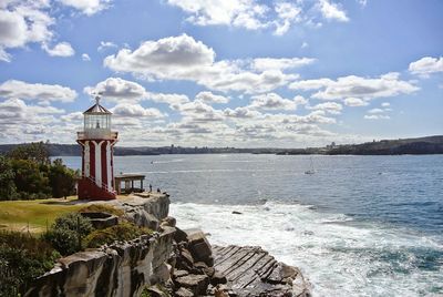 Lighthouse by sea against sky