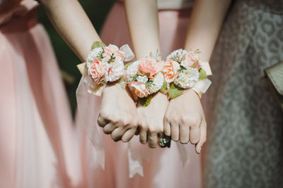 Midsection of bridesmaids showing flower bracelets in wedding ceremony