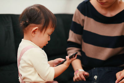 Close-up of mother holding baby and mobile phone at home