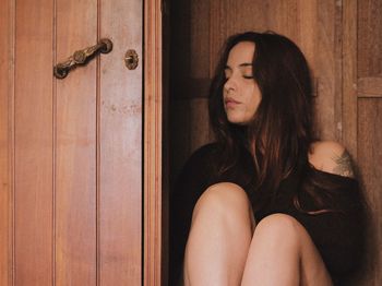 Woman sitting by wooden door at home