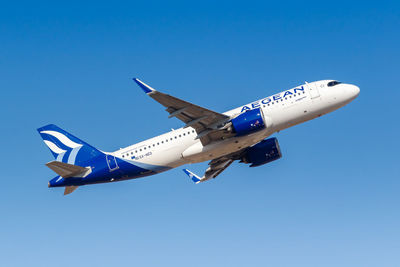 Low angle view of airplane flying against clear blue sky