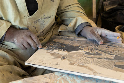 Selective focus of faceless craftsman working on hand made stone engraving of egyptian hieroglyphs