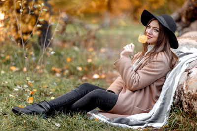 Portrait of young woman leaning wooden log at park