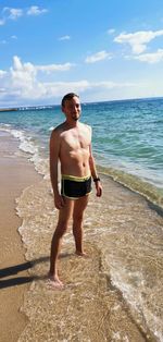 Full length of shirtless man standing on beach