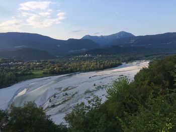 Scenic view of river by mountains against sky