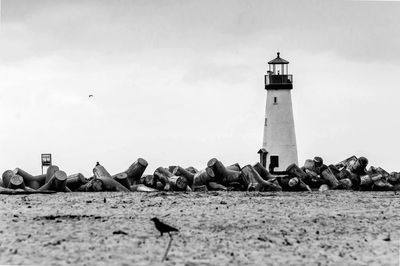 Lighthouse on beach against sky