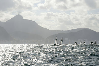 People on mountain by sea against sky