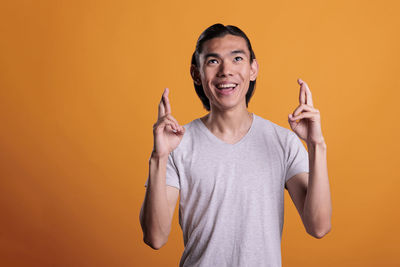 Portrait of young woman gesturing while standing against yellow wall