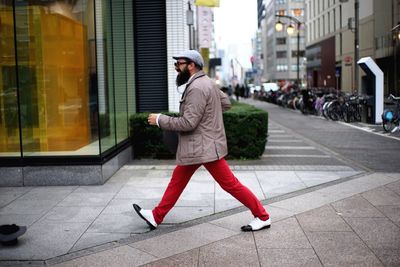 Full length of man walking on sidewalk in city