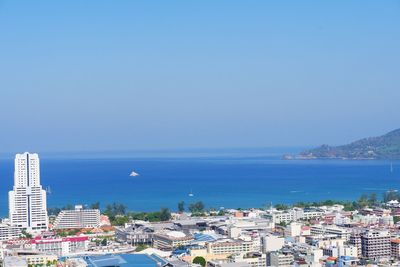 Scenic view of sea and buildings against clear blue sky