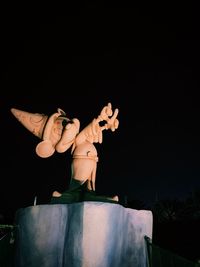 Low angle view of man statue against black background