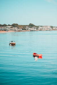 Rear view of woman kayaking in sea against clear sky