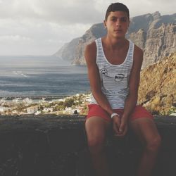 Portrait of young man sitting against sky