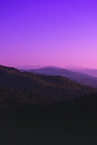 Scenic view of silhouette mountains against clear sky at sunset