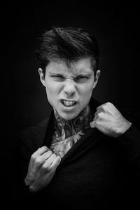 Portrait of young man against black background