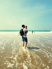 Young man with son standing at beach