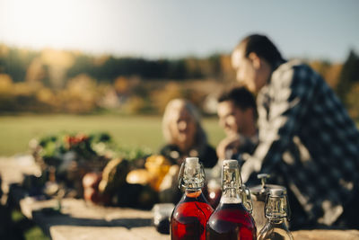 Drinks in airtight bottles on table with farmers discussing in background