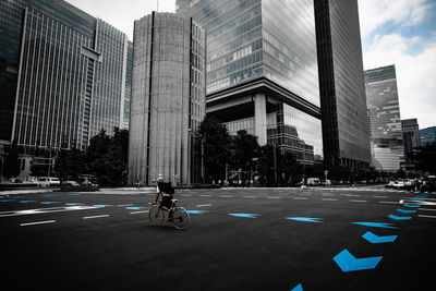 Man riding bicycle on road against buildings in city