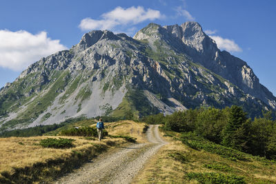 Rear view of man walking on mountain against sky