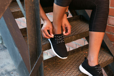 Low section of woman tying shoelace on metallic steps