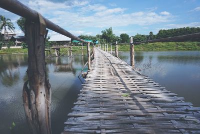 Wooden footbridge over river against sky