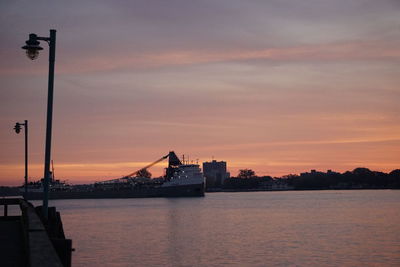 Silhouette of suspension bridge over river during sunset