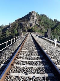 View of railroad tracks by mountain against clear sky