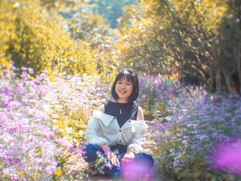 Portrait of woman sitting on purple flowering plants