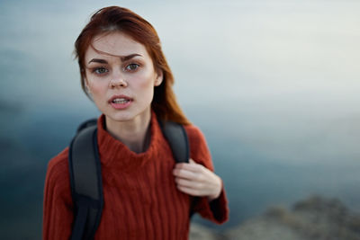 Portrait of young woman standing against sea