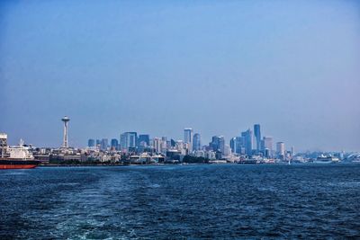 Sea and cityscape against clear sky