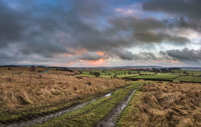 Scenic view of field against storm clouds