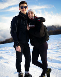 Portrait of young couple standing on snow covered land