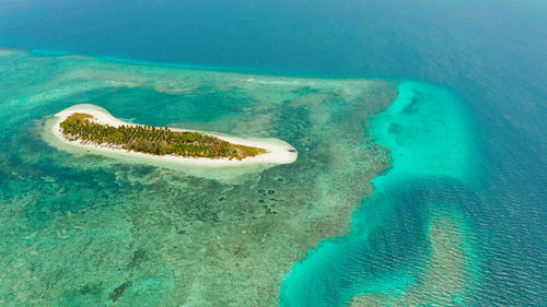 Tropical island on an atoll with beautiful sandy beach by coral reef from above. canimeran island 
