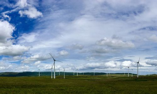 Windmills on field against sky