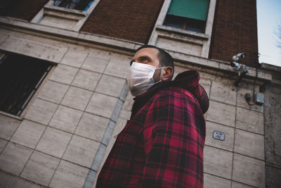 Full length of man with face mask standing against built structure